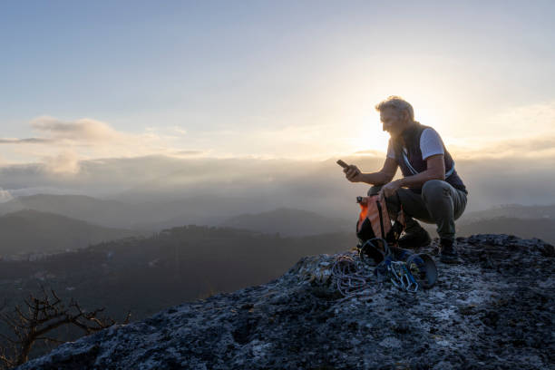 istock Mature hiker uses mobile phone on mountain top 2138867205