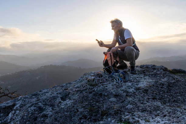 istock Mature hiker uses mobile phone on mountain top 2138867206