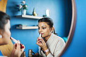 Young Indian woman applying lipstick
