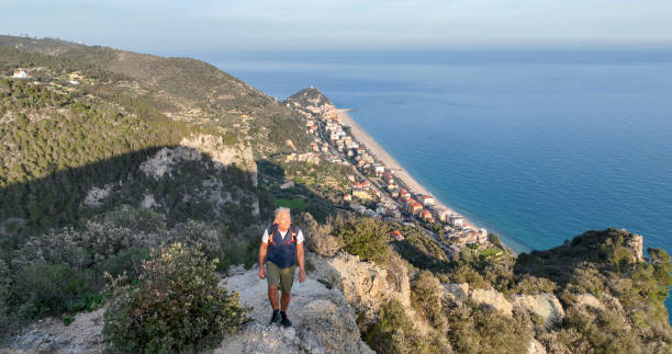istock Mature man ascends rock ridge crest above sea 2138868399
