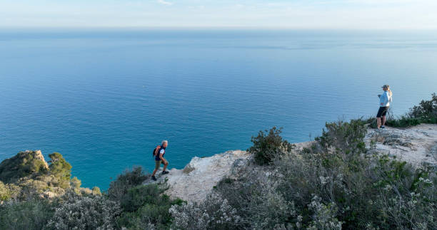 istock Mature couple ascend rock ridge crest 2138868533