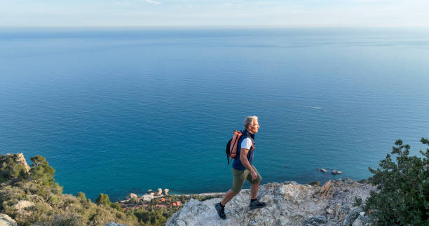 istock Mature man ascends rock ridge crest 2138868535