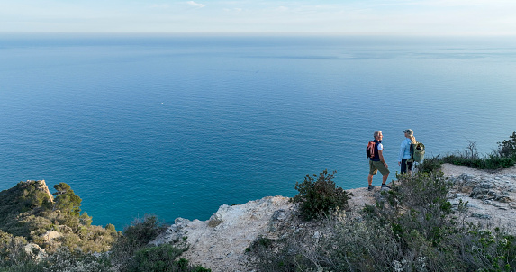 Aerial view of mature couple on cliff above sea,  Liguria