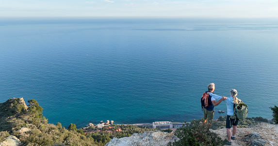 Aerial view of mature couple on cliff above sea,  Liguria