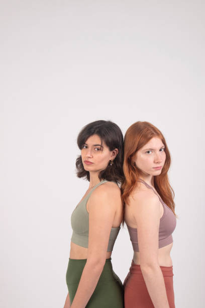 istock Two young women standing back to back, looking over their shoulders with confident expressions, isolated on a white background. 2138868874