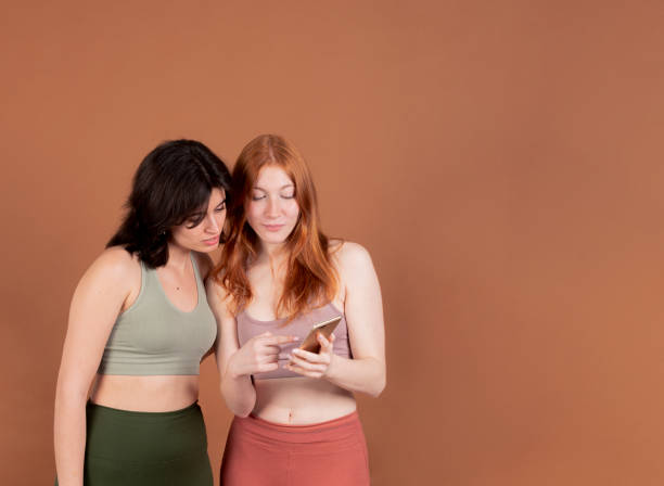 istock Two women looking at a smart phone together against a brown background. 2138868927