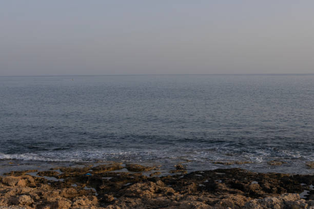 Serene view of the calm sea and rocky shoreline at dusk.