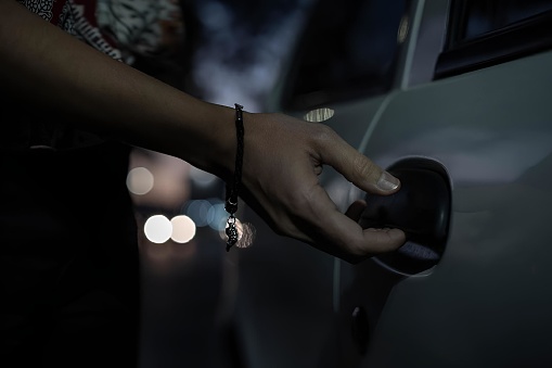 Woman's hand opening a car door, low light outdoors