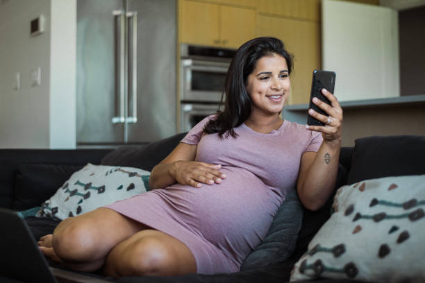 istock Pregnant woman at home using smart device for personal finance 2138893368