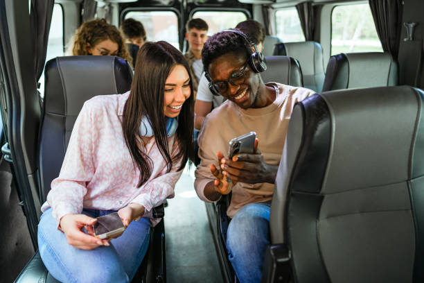 istock Friends looking at a mobile phone while sitting on the bus 2138893508
