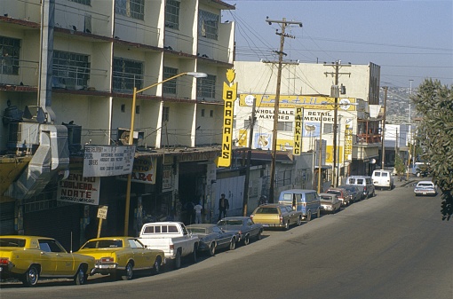 Los Angeles, California, USA, 1979. Street with parked cars, buildings and shops in a district of Los Angeles. Also: pedestrians.