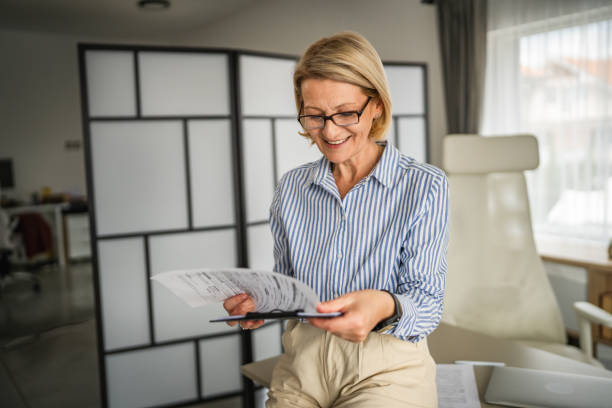 istock mature woman read contract document paper at office happy smile 2138898878