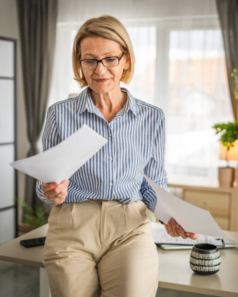 istock mature woman read contract document paper at office happy smile 2138901548