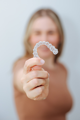 A hispanic woman with invisible dental aligner braces. lose-up of woman wearing orthodontic silicone trainer. Invisible braces aligner.