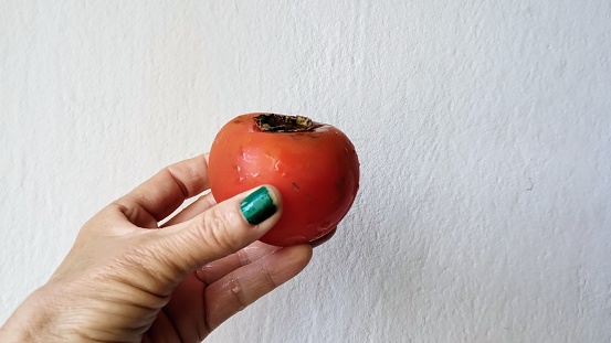 Hand holding a ripe persimmon