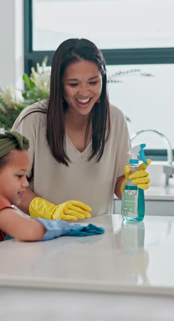 Home, mother and daughter with spray, wipe surface and teaching  with kitchen counter or housekeeping education. Parent, child development or mama with family or cleaning with table, cloth or talking