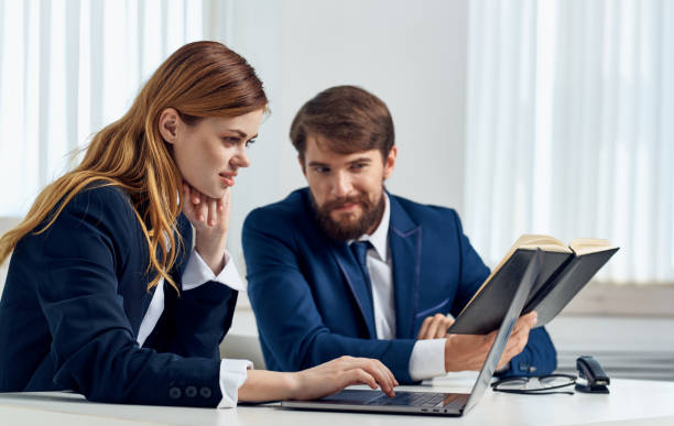 business man and woman sit at the table with open laptop in office and notepad documents model. High quality photo