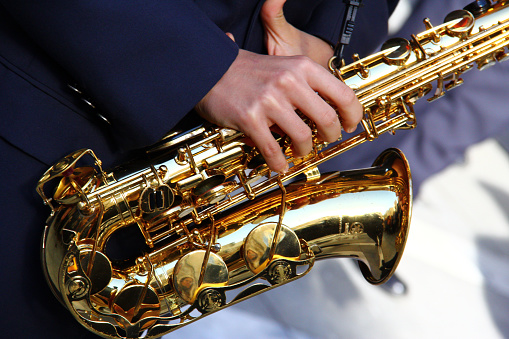 Military orchestra man performing during ceremony. Detail with musician hands playing on trumpet.