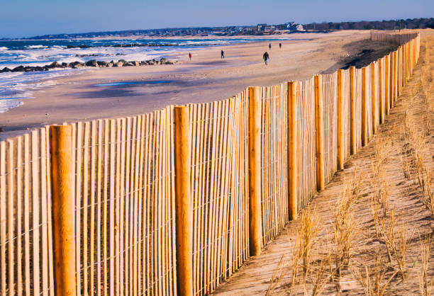 A few people brave the cold February winds to walk along Town Neck Beach in Sandwich, Massachusetts where a new sand fence has been installed to help control erosion.