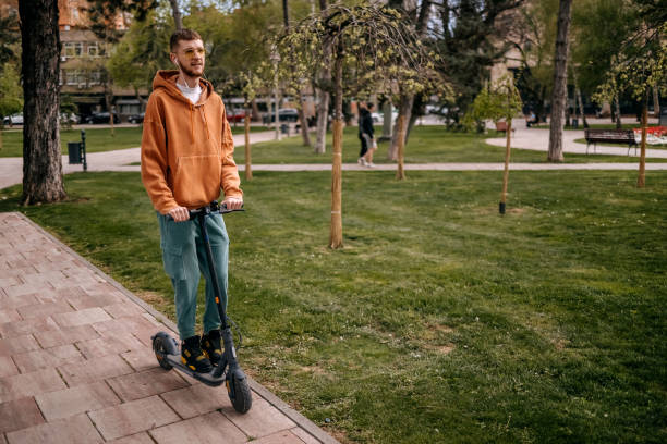 istock Young man relaxing in public park with driving electric scooter 2138976205