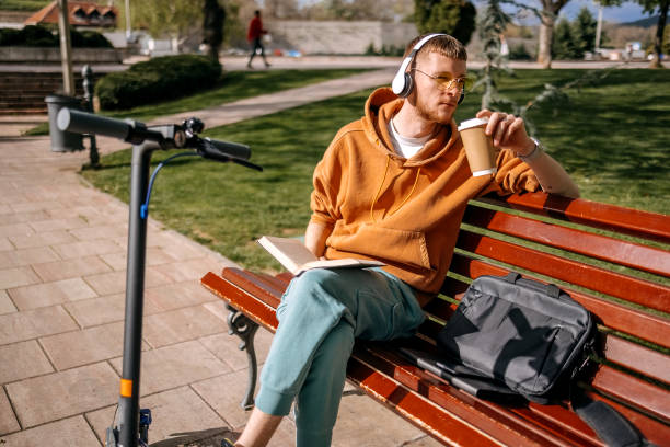 istock Young man relaxing in public park reading book and having coffee 2138977804