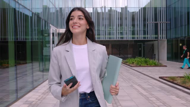 Young successful businesswoman using mobile phone while leaving the office.