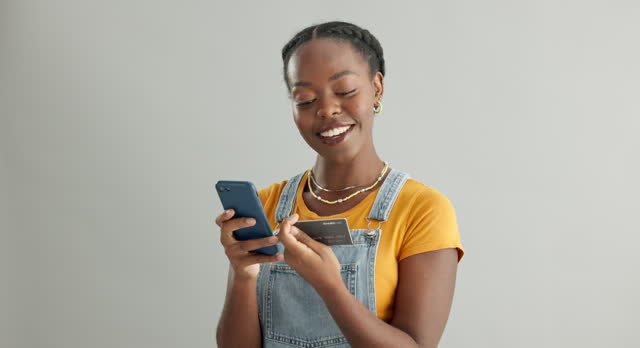 Online shopping, phone or black woman with credit card in studio for payment via internet website or fintech. Happy smile, white background or person typing money transfer via digital mobile banking
