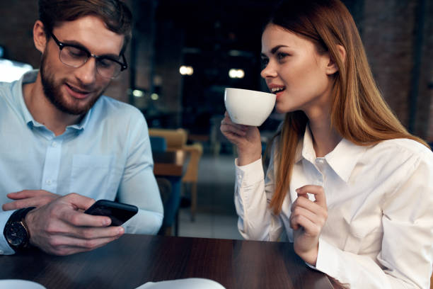 woman drinking coffee at the table next to a man work colleague technology. High quality photo