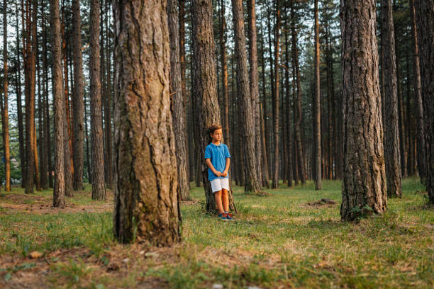 Handsome teenage boy standing in the forest