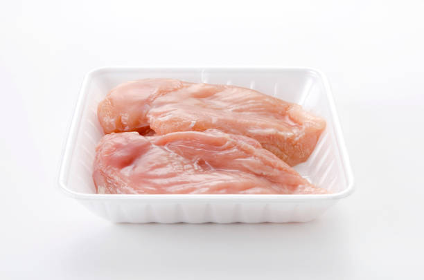 Raw Chicken breast on a foam tray on a white background