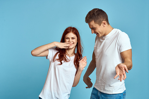 enamored man and woman in jeans and a T-shirt on a blue background hug each other and have fun. High quality photo