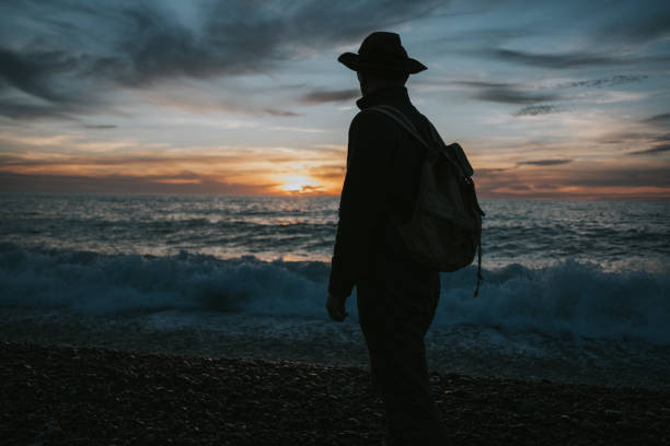 istock photo of man with backpack and hat at dramatic sunset 2139050207