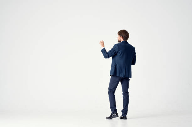 Gentleman in a blue suit gestures with his hands on a light background back view business finance. High quality photo