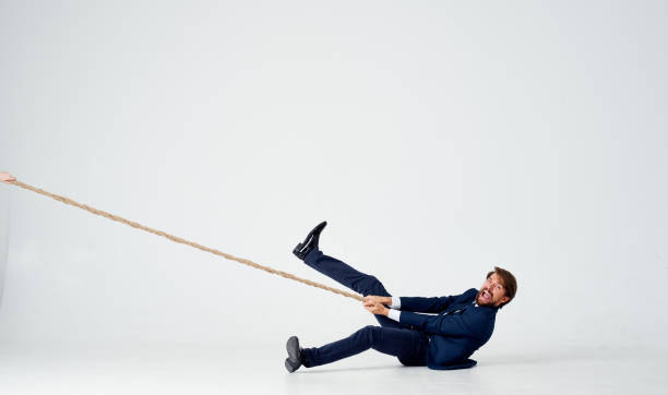 istock a business man lies on the floor and pulls a rope on a light background indoors 2139063991