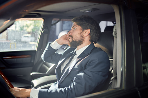 handsome man in suit driving a car trip talking on the phone finance. High quality photo