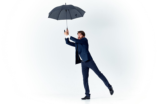 a gentleman with an open umbrella in a dark suit bent to the side. High quality photo
