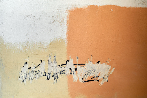 Art abstract wall wall with old graffiti inscription, multicolor painted white yellow orange texture background