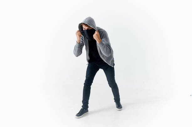 secretive masked man crouching sneaking robbery vandalism light background. High quality photo
