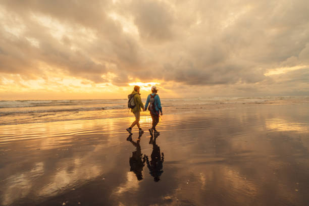 Active senior couple out at the sea beach enjoying a walk together by the sea at sunset.