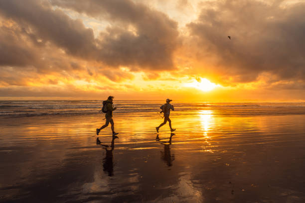 istock A happy couple running through waves at sunset beach. 2139092749