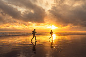 Couple at sunset running by the sea, enjoying outdoors.