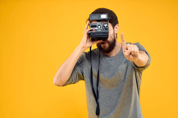 istock Male photographer with professional photo camera. Professional Creative approach studio yellow background 2139097469
