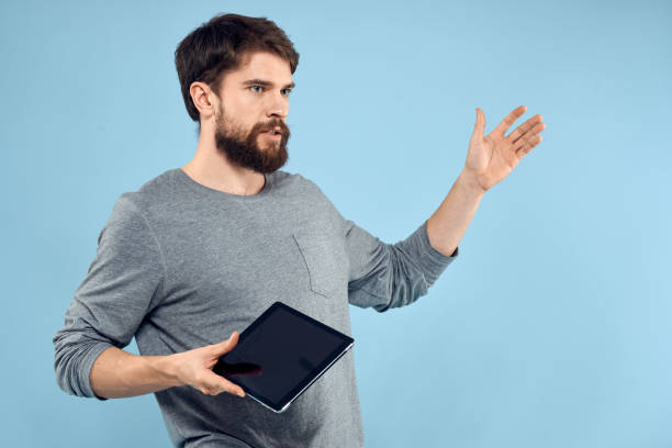 istock Man holding tablet in hands wireless technology internet lifestyle studio blue background emotions 2139111953