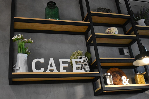 Coffee sign in Spanish Cafe, white letter in a minimalist decorated wall with fresh flowers and other decorations.