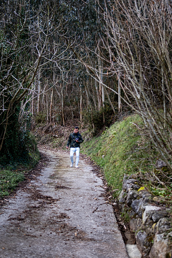 Man in camouflage hoodie captures biodiversity, exploring rural Asturias.