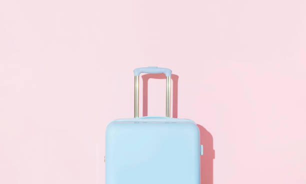 istock Blue suitcase on a pastel pink background with long deep shadows. Travel concept 2139176561