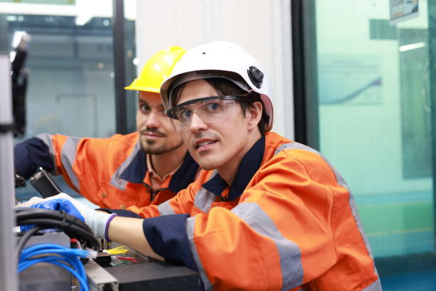 istock Two skilled mechatronics engineers, equipped with safety PPE, are diligently conducting maintenance and configuring an advanced automation system at the factory. 2139209406