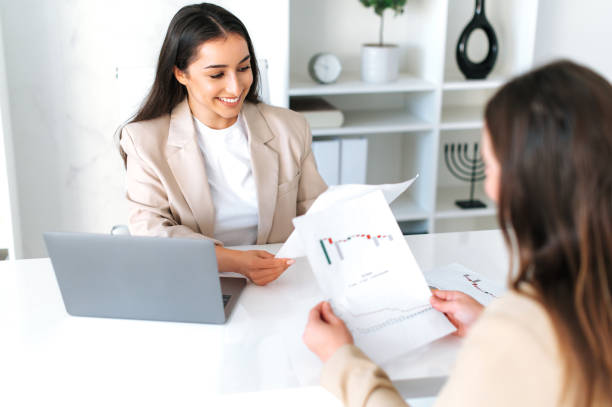 istock Brainstorm, partnership concept. Two successful female colleagues are sitting at a desk, discuss financial strategy in modern office space, analyzing financial report, planning business plan, smile 2139225574