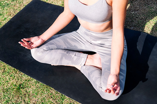 detail of the crossed legs of a woman doing meditation sitting on a yoga mat, concept of mental relaxation and healthy lifestyle