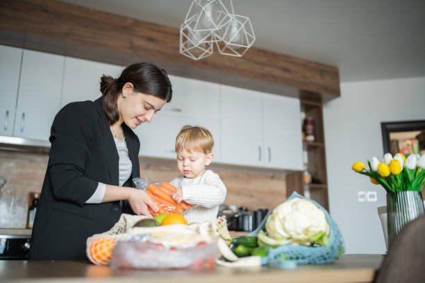 istock Cheerful mother and son with groceries standing at dining table in kitchen. 2139294276